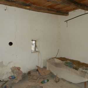 Interiér chyžky, posteľ s voľne uloženou slamou a otvor do komínového prieduchu v stene